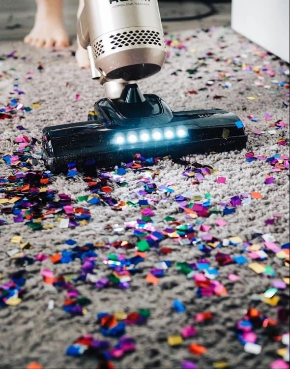 Vacuum cleaning colorful confetti on carpet